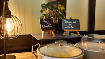 Taula amb una olla de sopa, un cartell que indica 'Saucisse de Vopaille' i un altre amb 'Oeufs brouilles'.