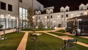 Un patio con mesas al aire libre, un árbol de Navidad y un camión antiguo.