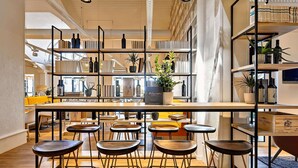 A modern interior with a central bar area, multiple seating options, and a variety of books and decorative items on shelves. - ibis La Roche sur Yon (Mouilleron-le-Captif)