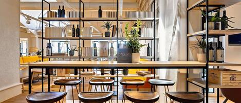 A modern interior with a central bar area, multiple seating options, and a variety of books and decorative items on shelves.