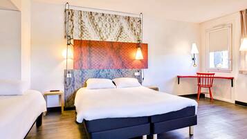 A hotel room with a large bed, a desk, and a chair.