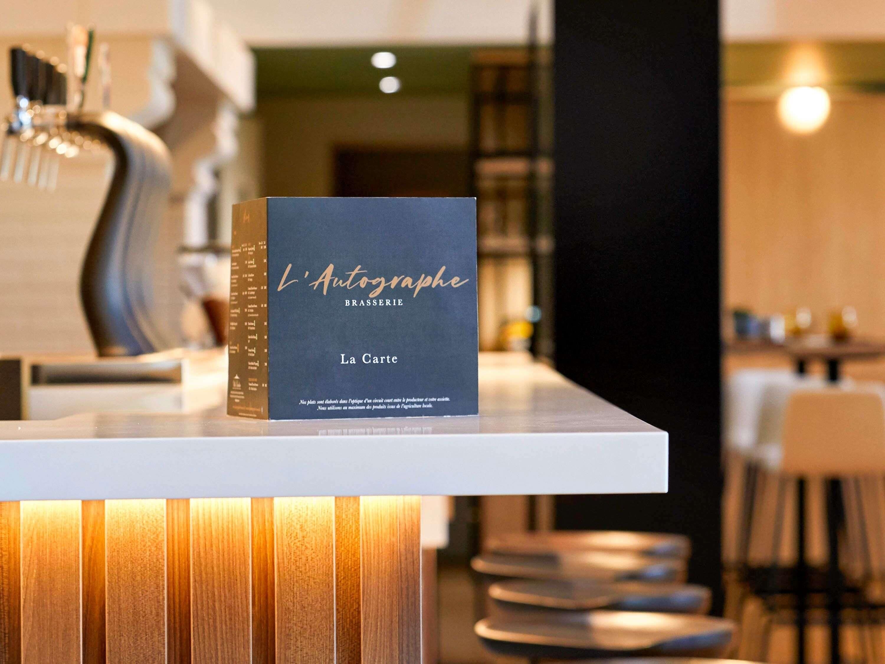 A book titled 'L'Autographe' on a table in a modern, well-lit room with a sleek design.