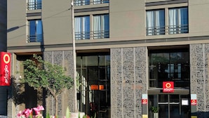Een modern gebouw met een glazen gevel, decoratieve metalen panelen en de aanduiding 'adagio'.