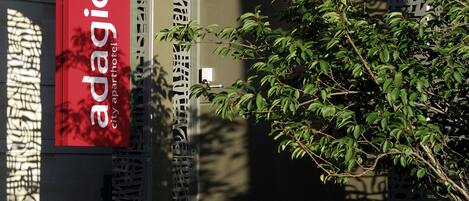 A building entrance with a sign for 'adagio city apartment hotel'.
