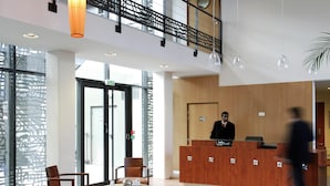 Een hotel lobby met een receptiebalie, een zithoek en een trap.