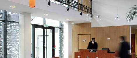 A hotel lobby with a reception desk, seating area, and a staircase.