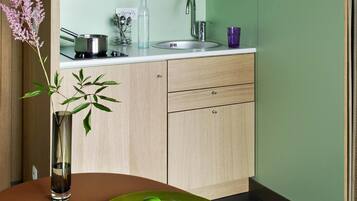 Una cocina con un lavabo, un florero con una planta, y un plato con limones.
