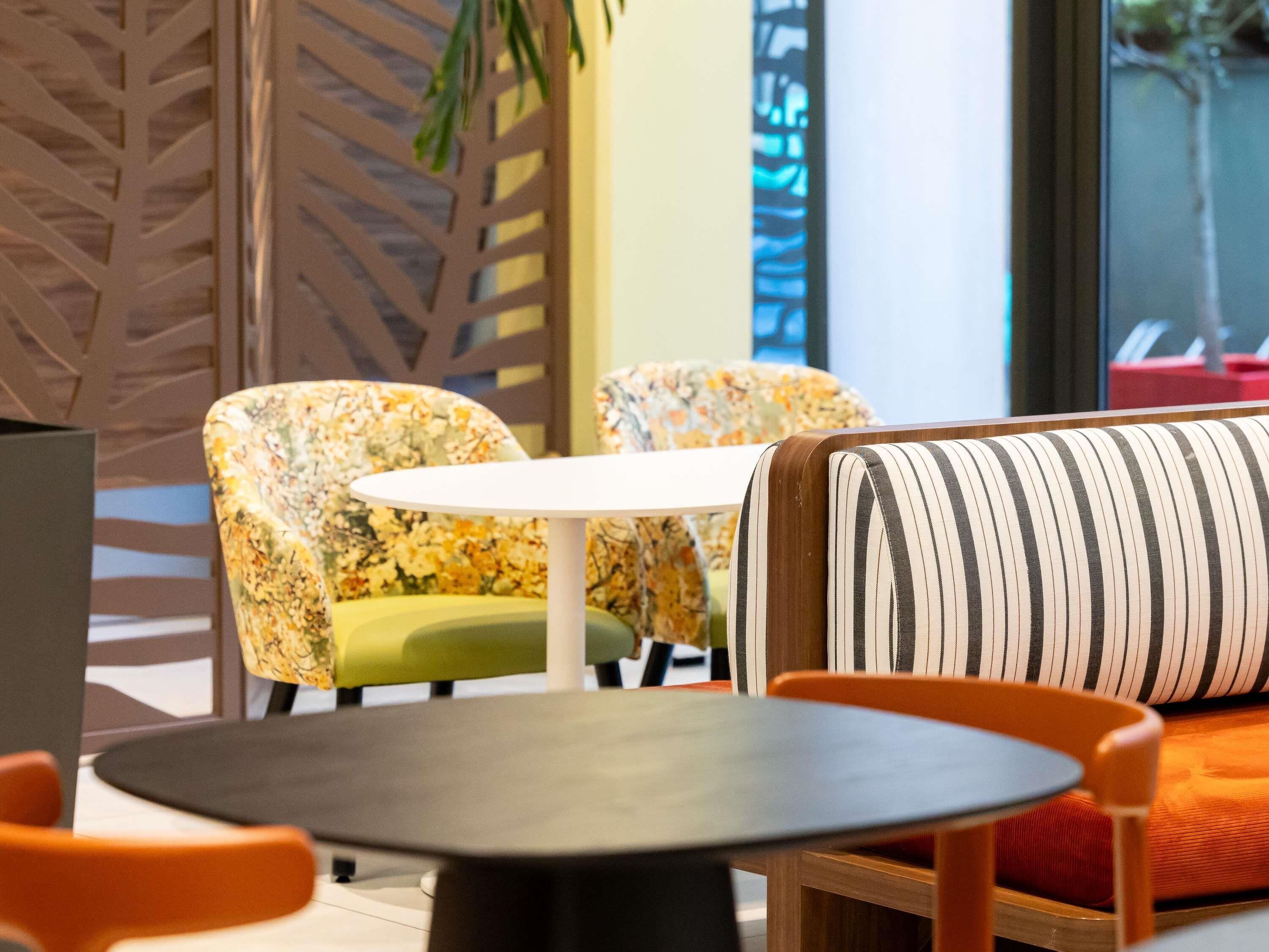 Een modern interieur met een ronde tafel, stoelen met bloemenprint en een gestreepte bank.