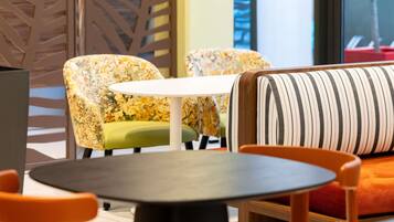 Een modern interieur met een ronde tafel, stoelen met bloemenprint en een gestreepte bank.