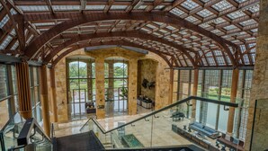 A spacious interior with a high ceiling, large windows, and a staircase. - Sofitel La Reserva Cardales (Campana)
