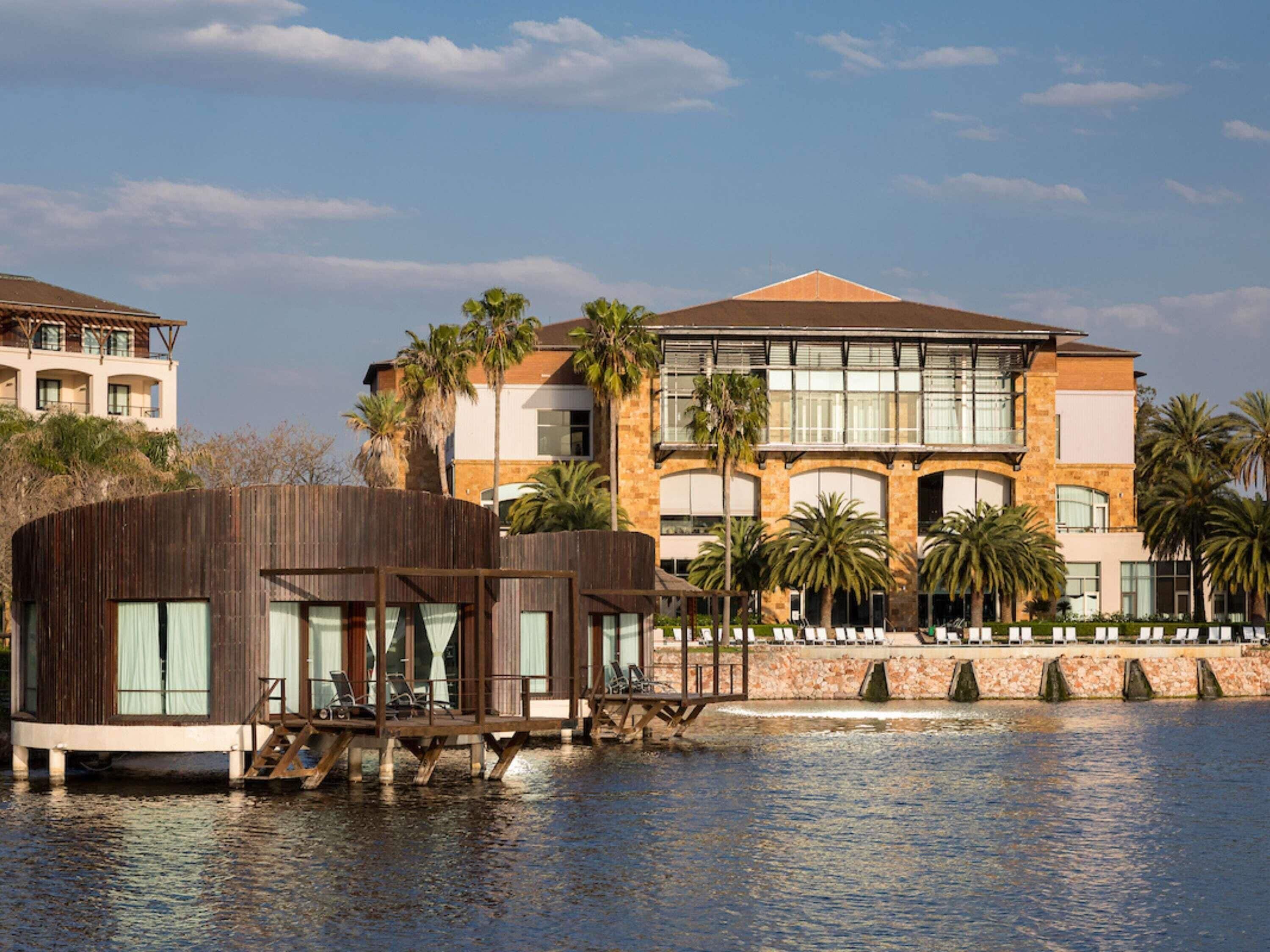 Hotel amb vista al mar, un moll de fusta, un edifici gran amb nombroses galeries i palmeres.