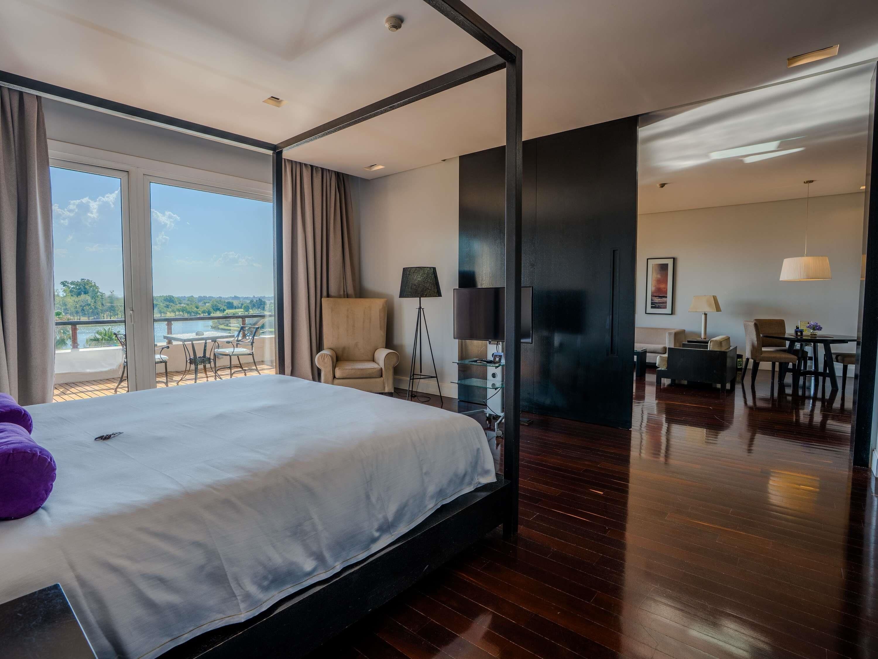 Habitación de hotel con una cama grande, una silla, un escritorio y vistas al exterior.