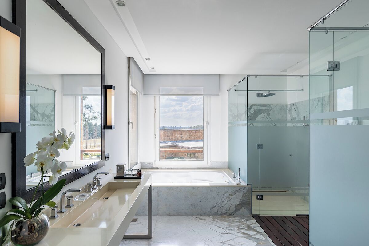 Un baño moderno con un espejo grande, una bañera y un box de ducha de vidrio.