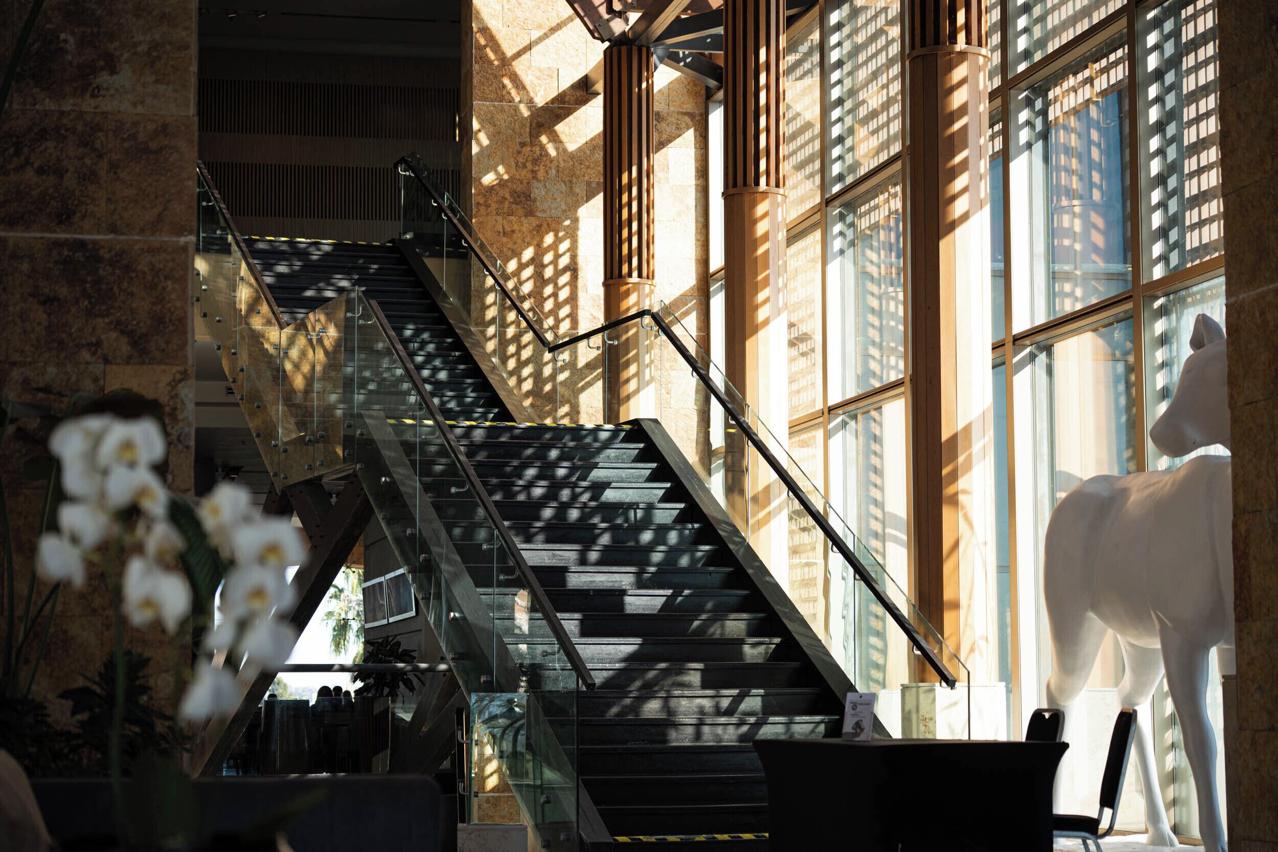 A staircase with metal railings, a glass balustrade, and a white statue.