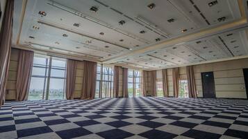 A large, open room with a checkered floor, large windows, and a high ceiling with multiple light fixtures.