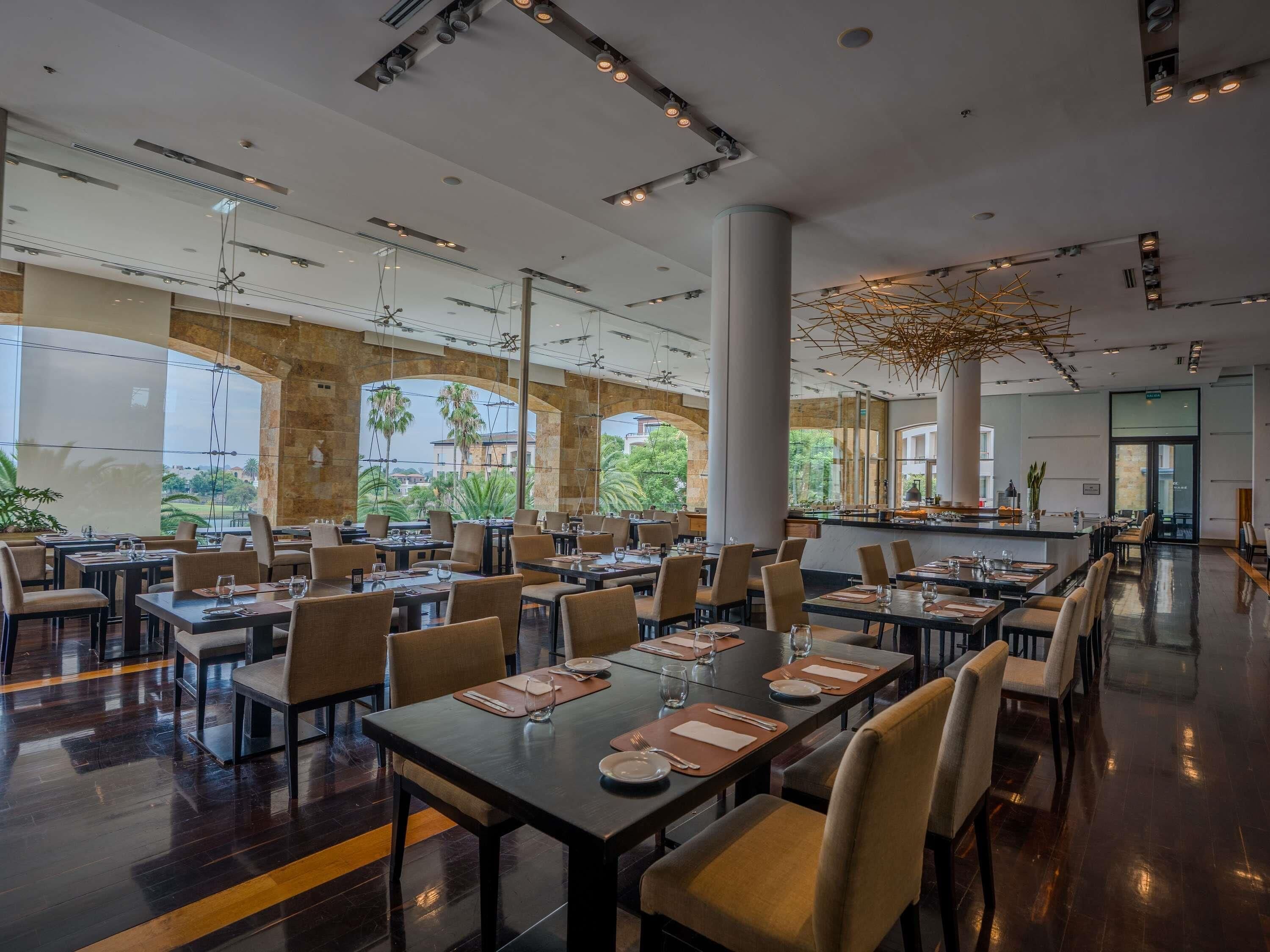 A spacious restaurant with high ceilings, large windows, and a modern interior design.