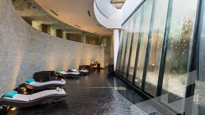 A modern spa area with reclining chairs and a glass wall. - Sofitel La Reserva Cardales (Campana)
