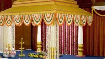 A decorated event space with a central canopy, draped curtains, and floral arrangements.