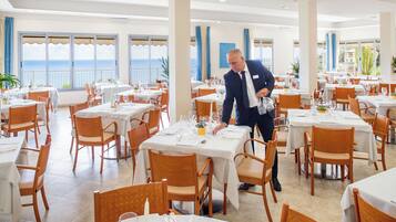 A restaurant with multiple tables, each set with white tablecloths, chairs, and dining utensils.