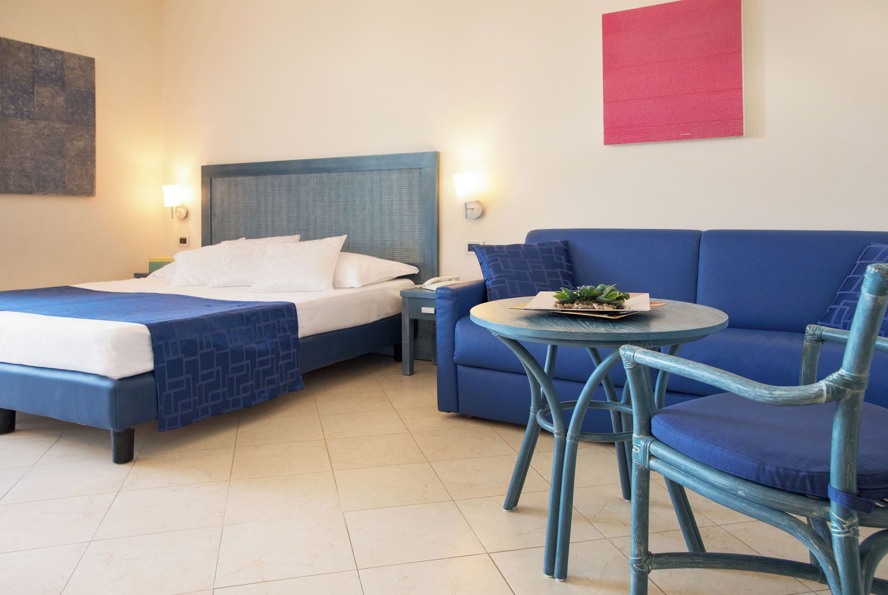 Une chambre d’hôtel avec un lit, un canapé, une petite table et une chaise.