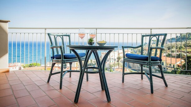 Un balcón con dos sillas y una mesa, con vistas a la costa.