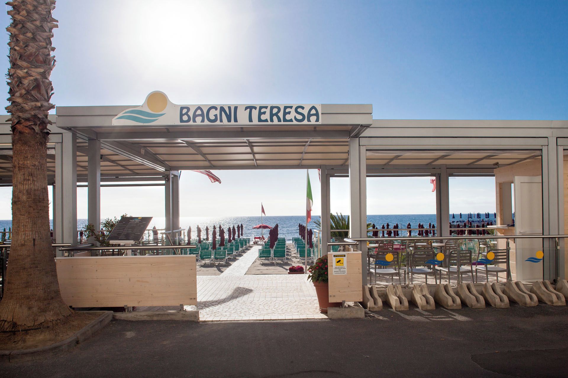 Un espacio al aire libre cubierto con un letrero que dice 'BAGNI TERESA' y vista al mar.