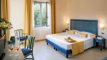 Ein Hotelzimmer mit einem Bett, Nachttischen, einem Schreibtisch mit zwei Weingläsern und einem Sessel.