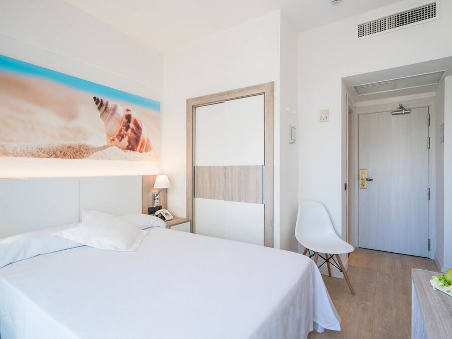 Een hotelkamer met een bed, een bureau, een stoel, een schilderij en een deur.