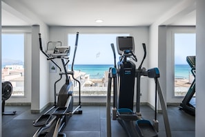 Une salle de sport équipée de machines de cardio et offrant une vue sur la plage.