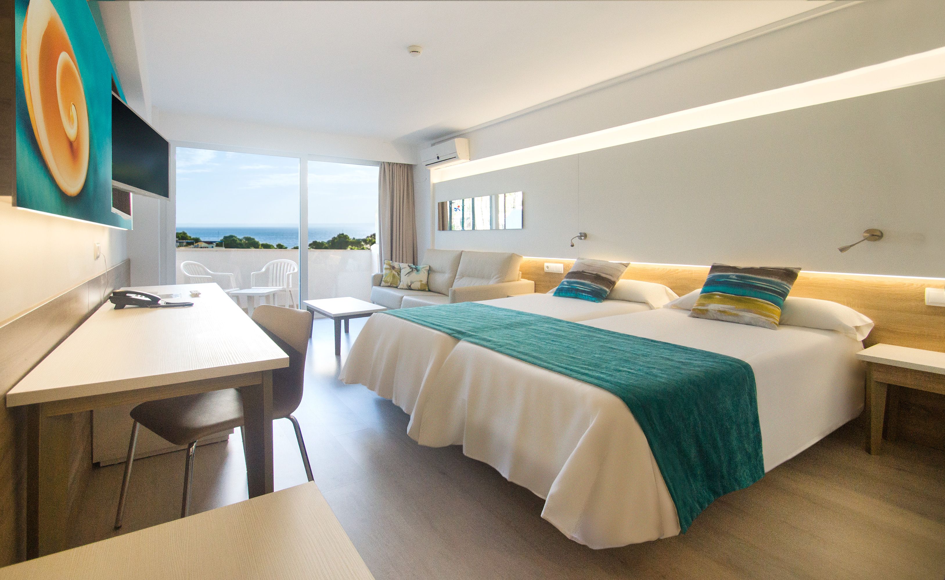 Una habitación de hotel con una cama, un escritorio y vista al mar.