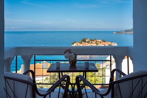 Ein Balkon mit Tisch und Stühlen mit Blick auf eine Küstenstadt, Gebäude und das Meer.