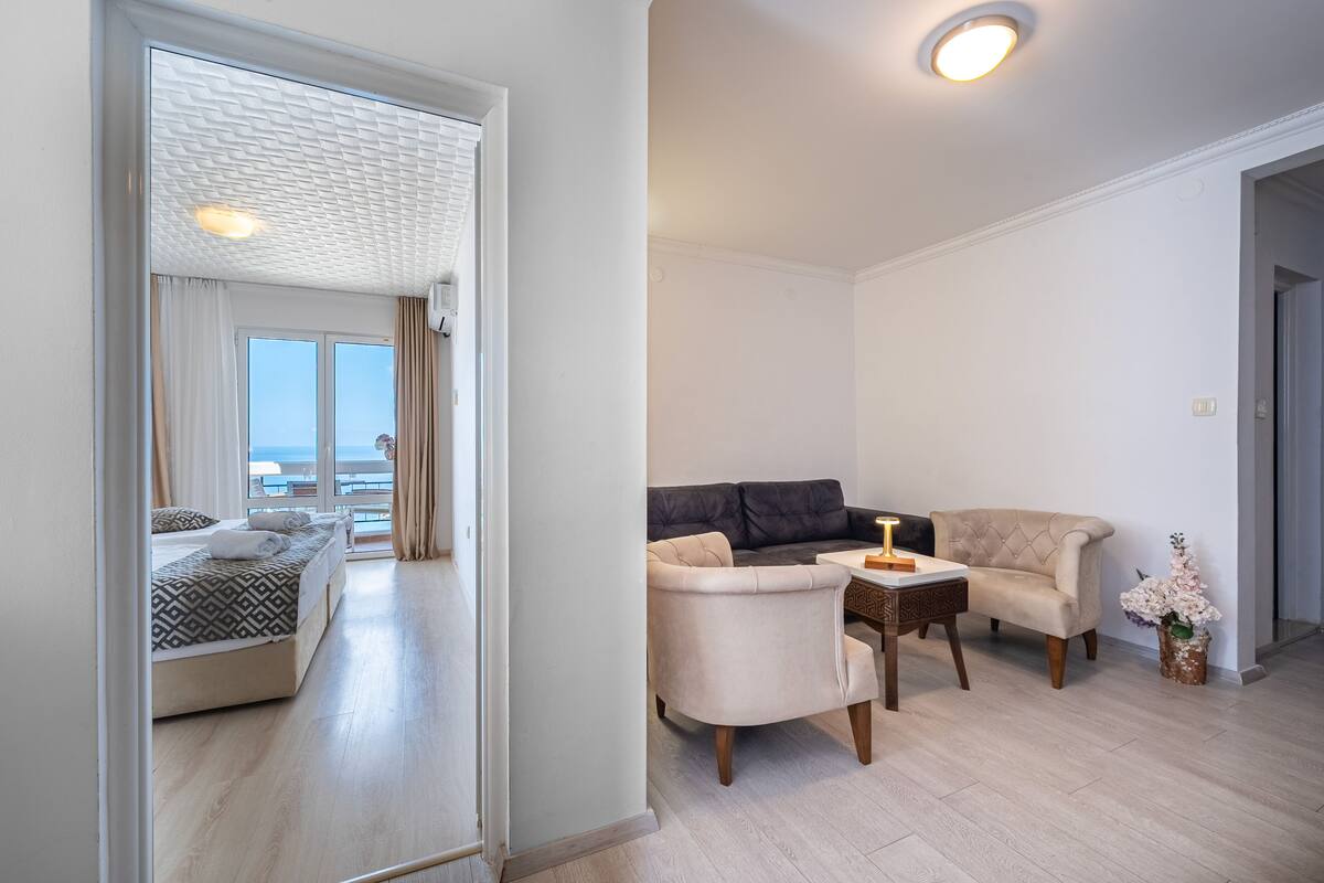 Une chambre d’hôtel moderne avec balcon, un ensemble de canapés et une table à manger.