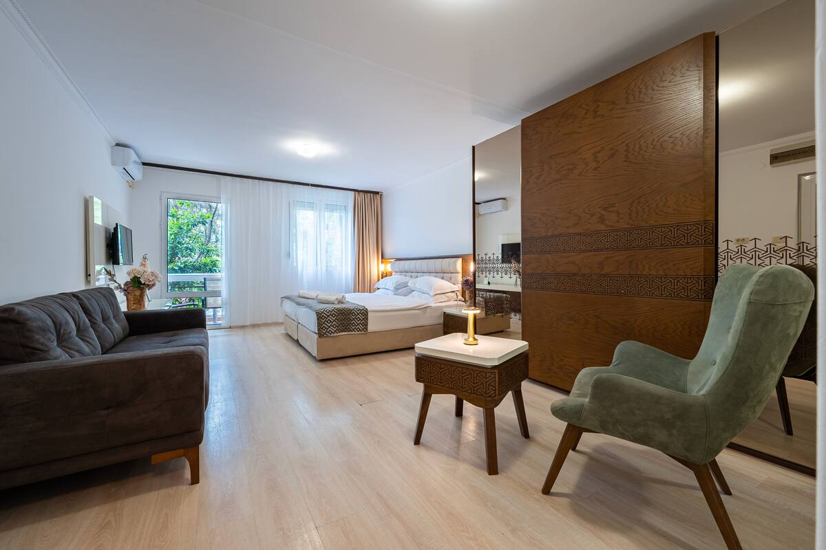 Une chambre d’hôtel moderne équipée d’un lit, d’un canapé, d’une chaise et d’une petite table avec une lampe.