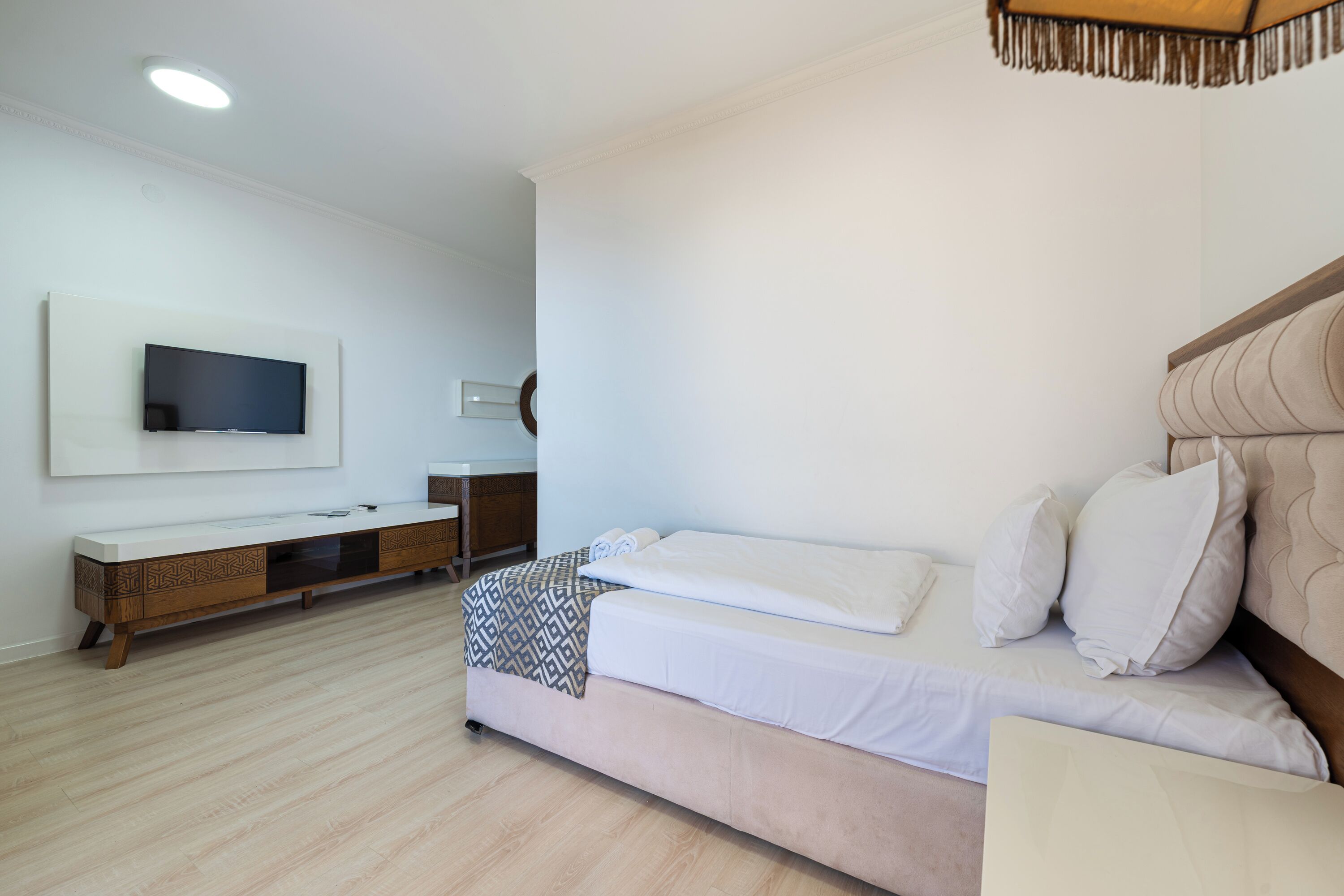 Un dormitorio moderno con una cama, un televisor montado en la pared y un elegante aparador de madera.