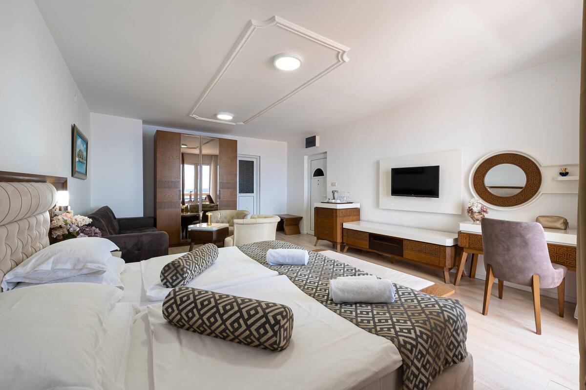 Une chambre d’hôtel avec un grand lit, un bureau, une chaise, une télévision et un miroir.