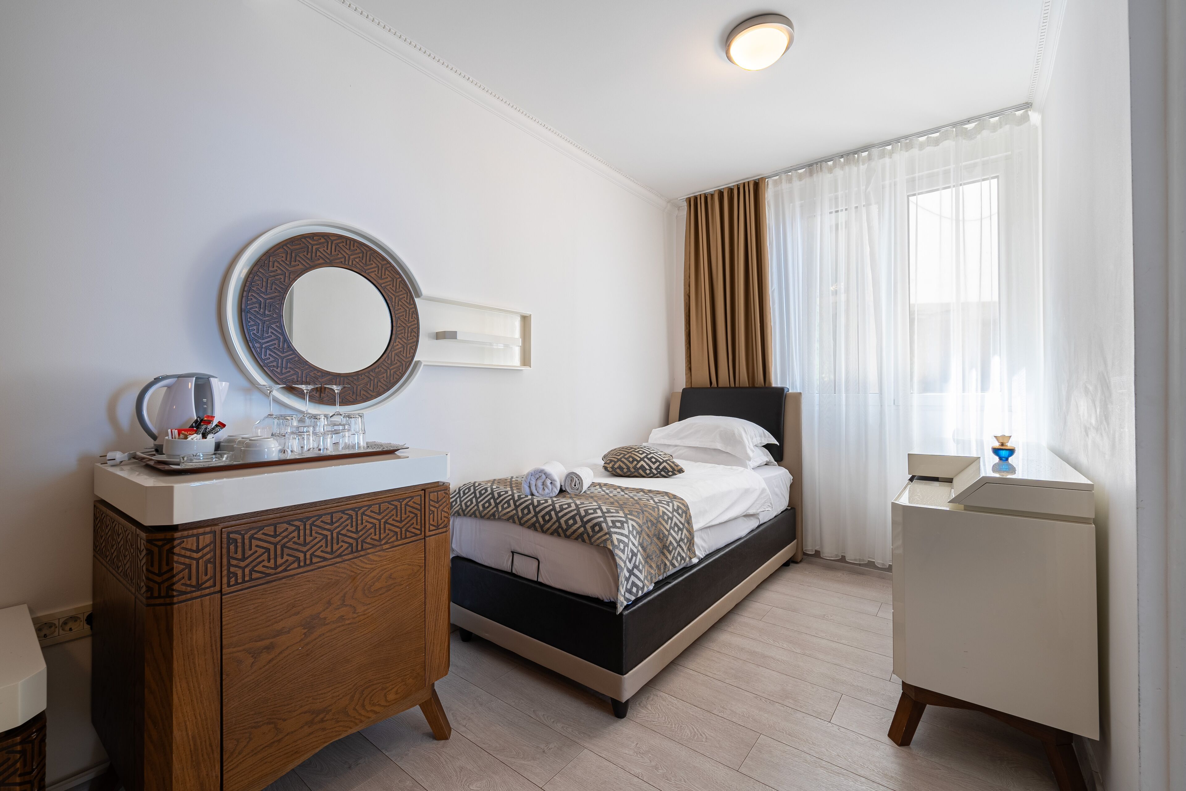 A bedroom with a bed, bedside table, dresser, and a mirror.