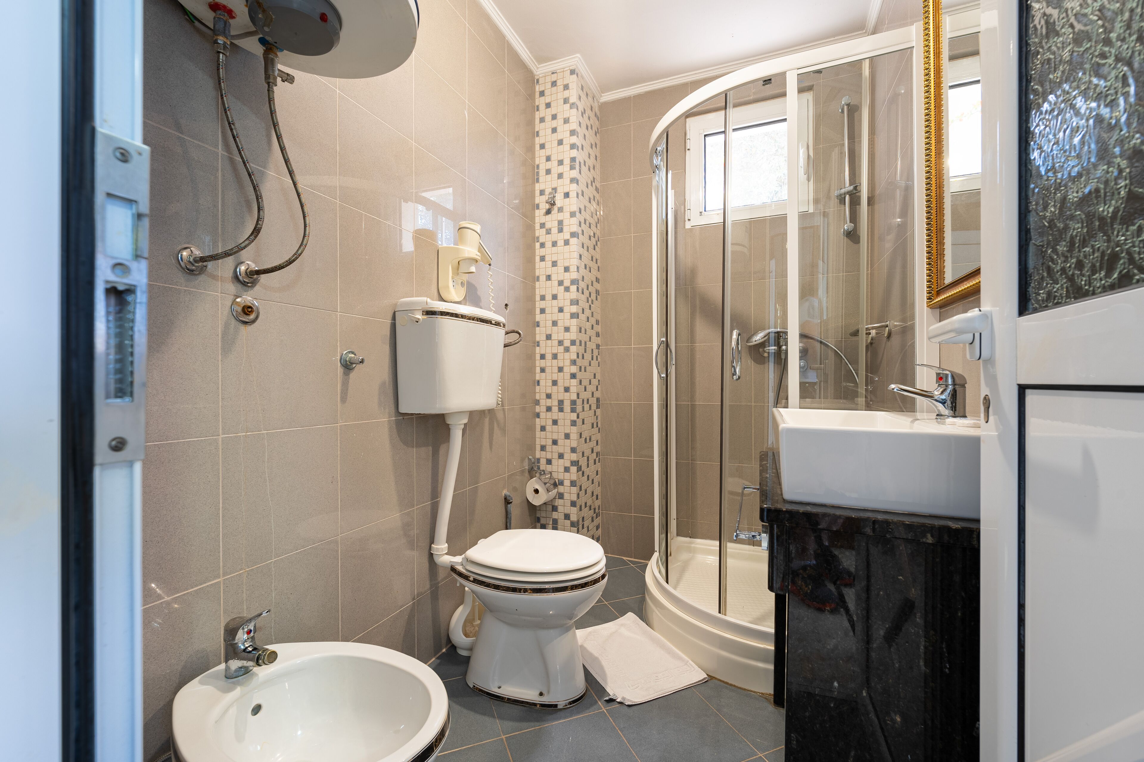 Un baño moderno con inodoro, bidé, lavabo y zona de ducha.