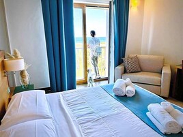 Una habitación de hotel con cama, sofá, balcón y vistas al mar.