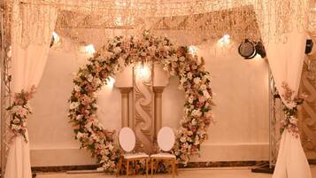 An indoor setting with a floral arch, two chairs, and a chandelier.