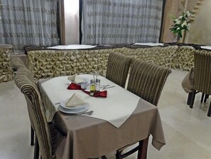 A dining area with a table set for four, including plates, cutlery, and condiments. - Indiana Hotel Cairo (Giza)