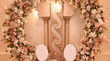 A room with a floral arch and two white chairs.