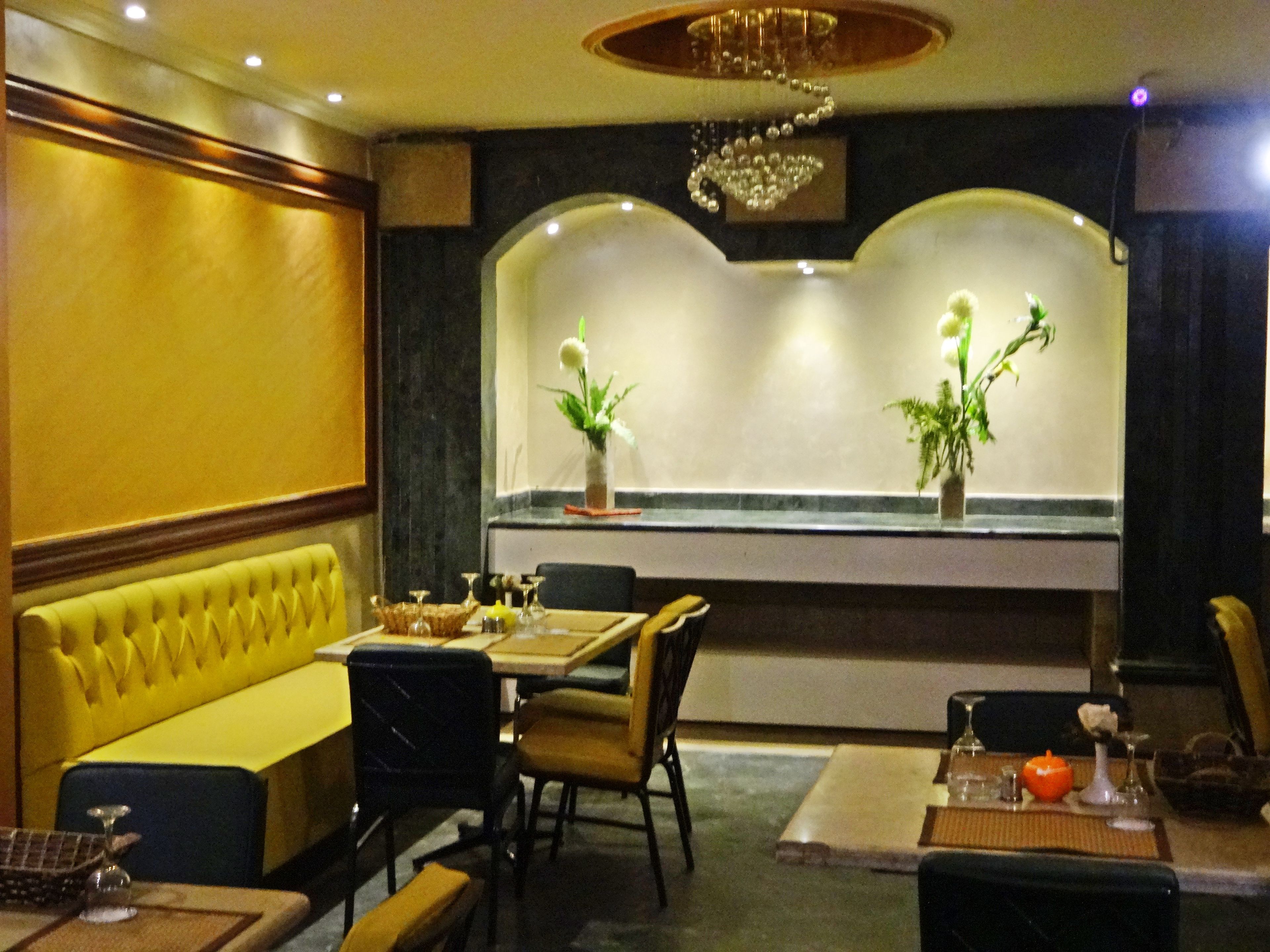 A dining area with a booth seating arrangement, a table set with dinnerware, and a decorative plant on the wall.