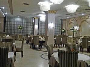 A banquet hall with round tables and chairs, chandeliers, and curtains. - Indiana Hotel Cairo (Giza)