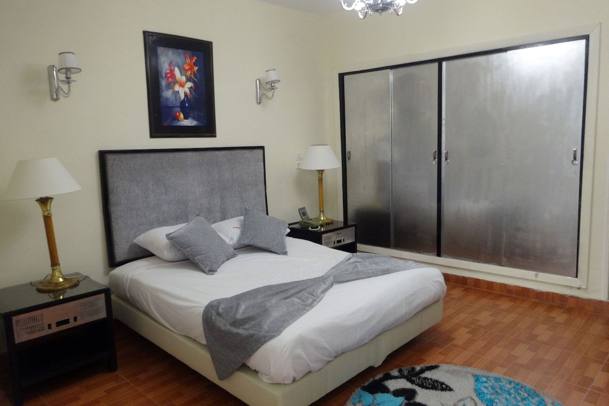 Un dormitorio con cama, mesitas de noche, armario y candelabro.