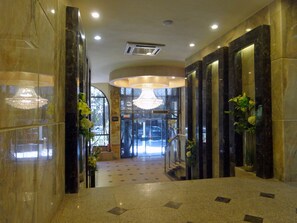 A hotel lobby with marble flooring, a grand chandelier, and a reception desk. - Indiana Hotel Cairo (Giza)
