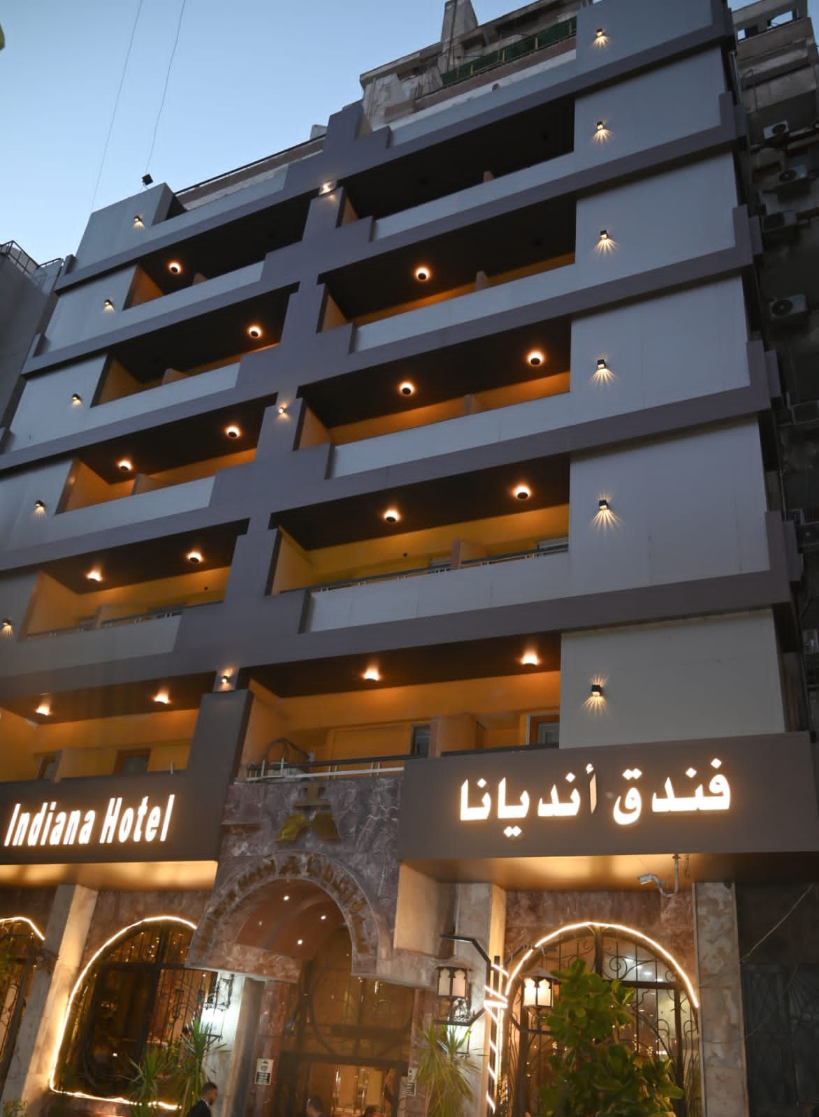 A multi-story hotel with balconies and a sign indicating 'Indiana Hotel' and 'Indiana Hotel' in Arabic.