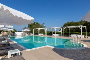 Una piscina al aire libre, sombrillas, tumbonas