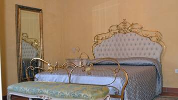 A bedroom with a bed, a bench, a mirror, and a nightstand.