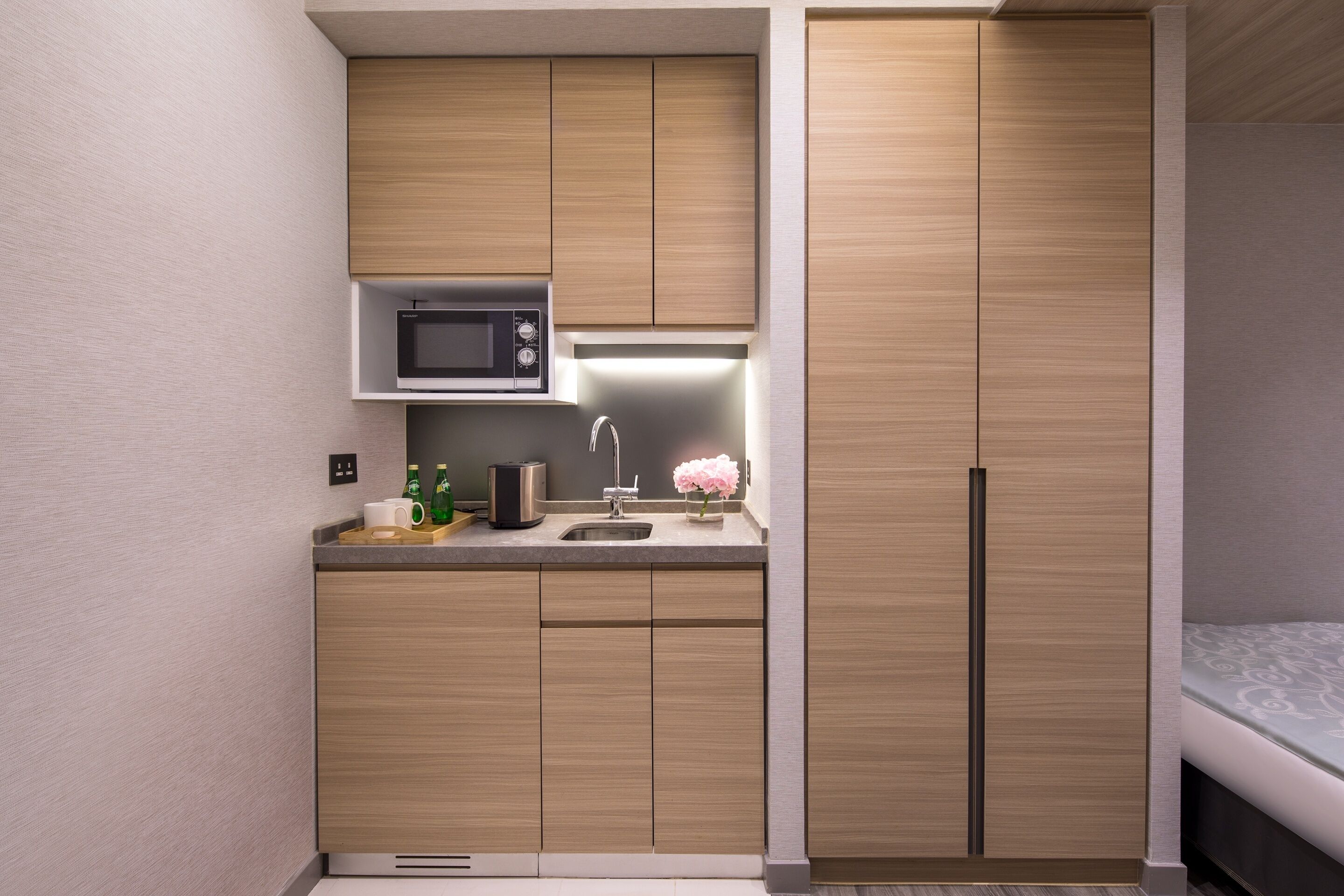 A modern kitchen with wooden cabinets, a microwave, a sink, and a refrigerator.