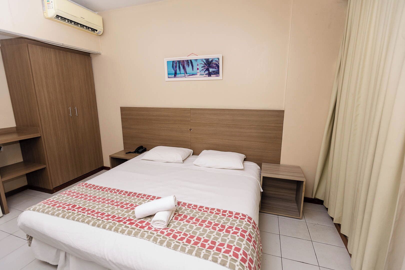 Ein Hotelzimmer mit Bett, Nachttisch, Schrank und einem Bild an der Wand.